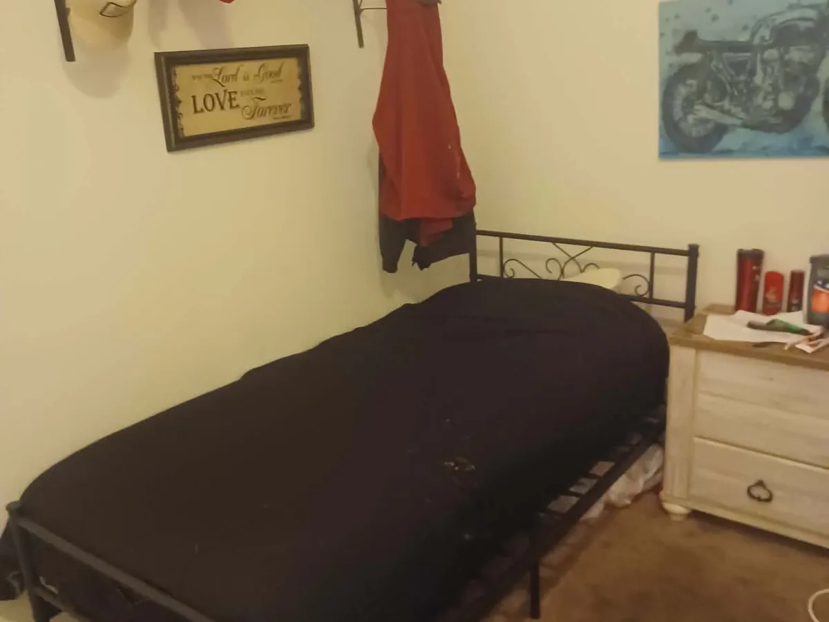 A resident bedroom with a twin bed, nightstand, and wall rack.